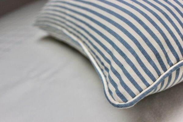 A Candy Stripe - Blue pillow on a bed.