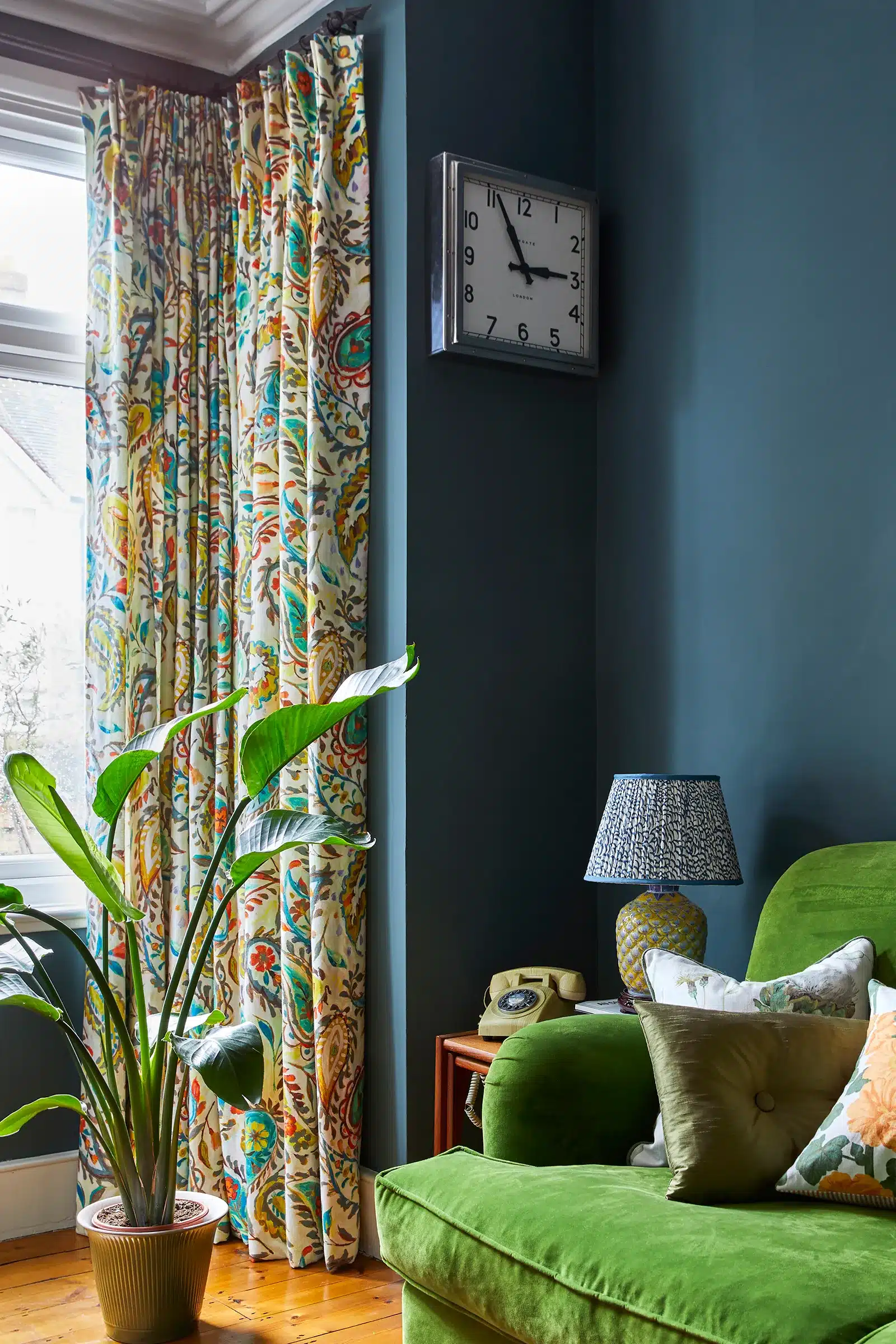 A living room with a green couch and made-to-measure colorful curtains.