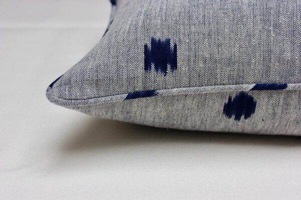 A grey and Blue Ikat pillow with a polka dot pattern.