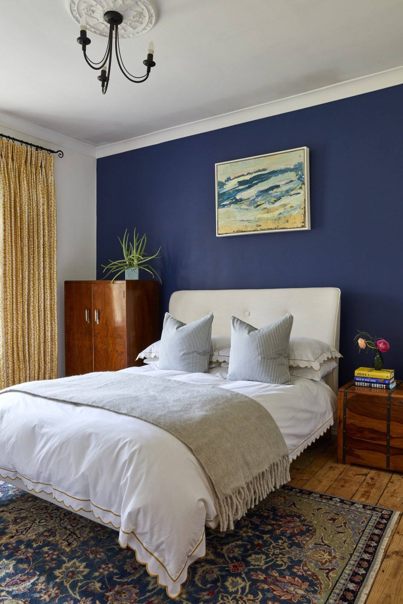 A bedroom with blue walls and a rug on the floor.