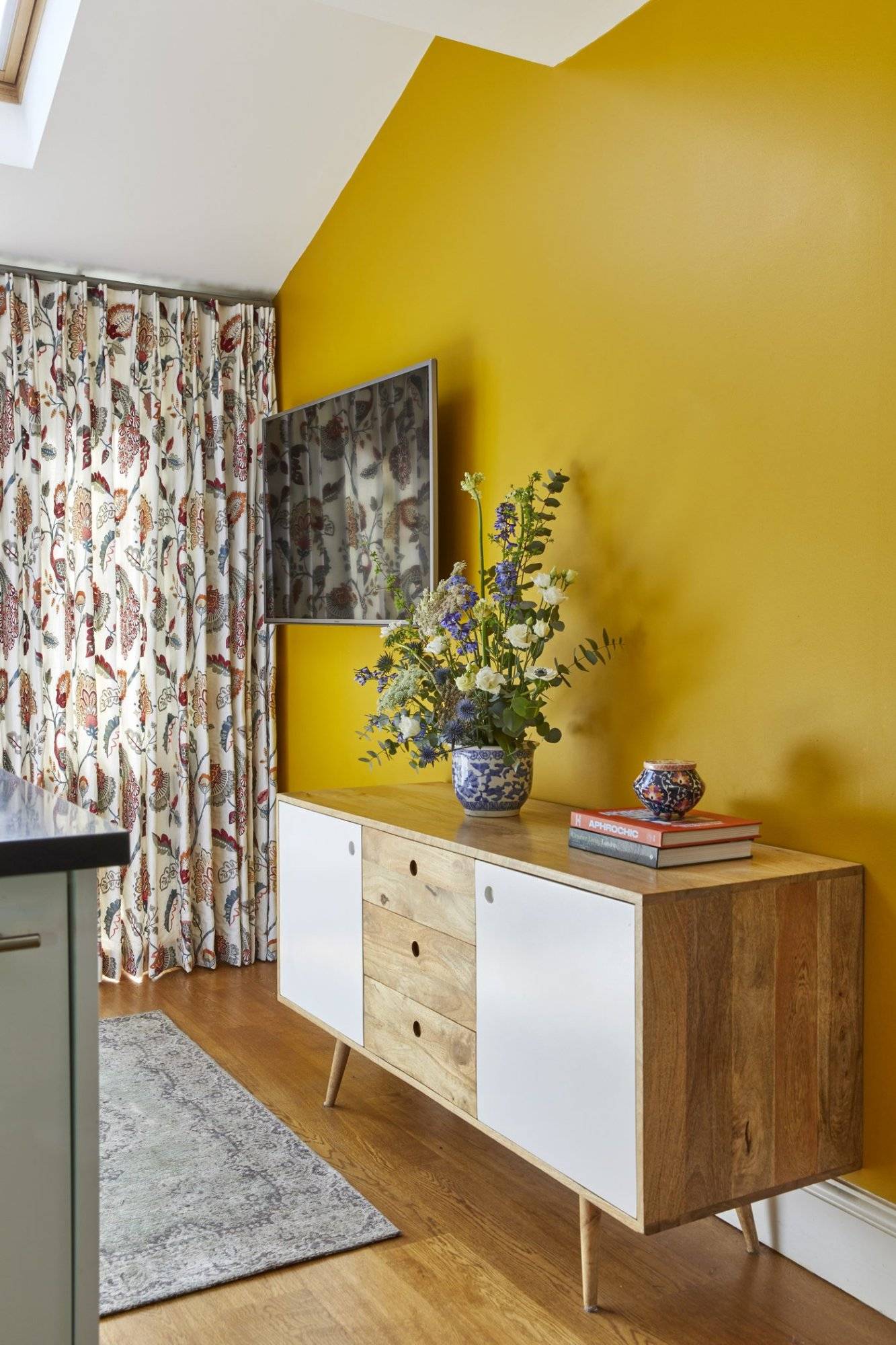 A kitchen with yellow walls and a wooden cabinet.