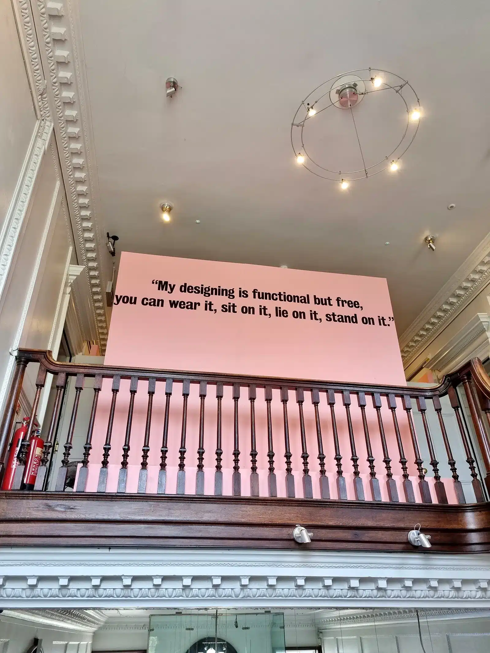A room with a pink railing and a quote on the wall.