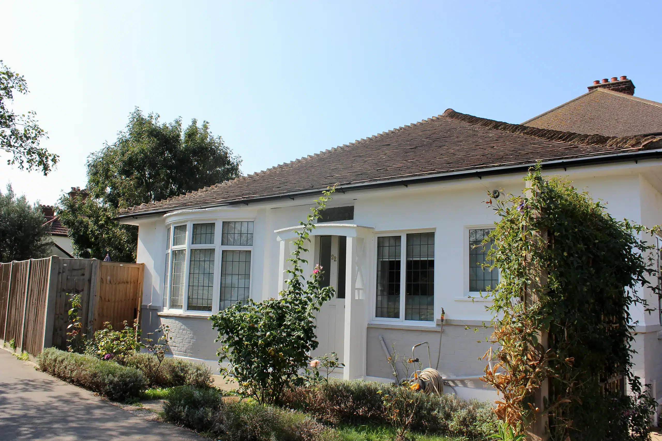 A house with bushes in front of it and a fence.