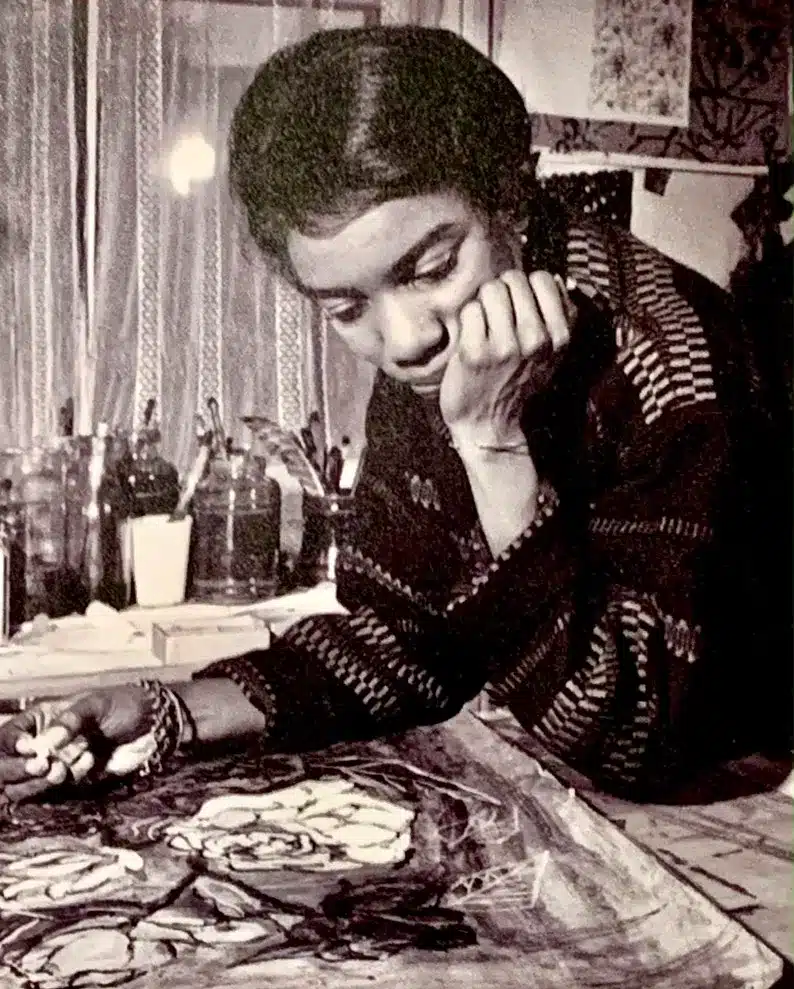 An old black and white photo of a woman drawing on a piece of paper.