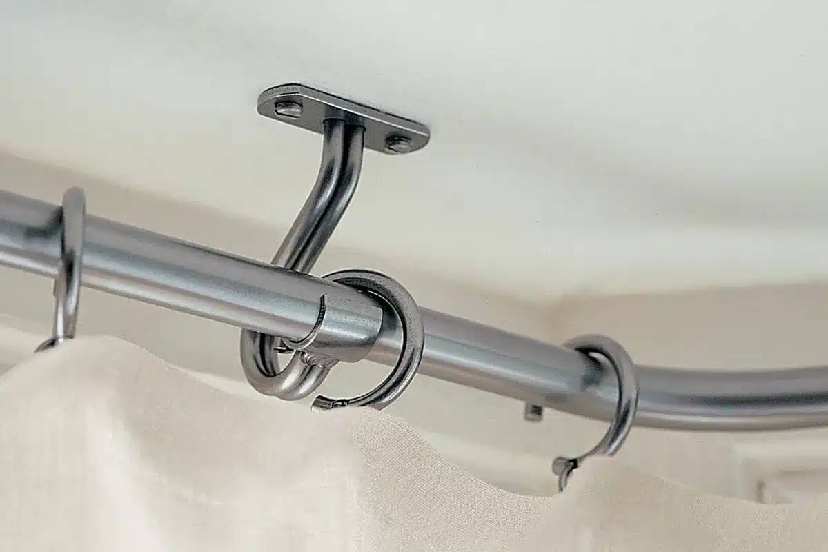 A curtain rod with a hook attached to it for bay window curtains.