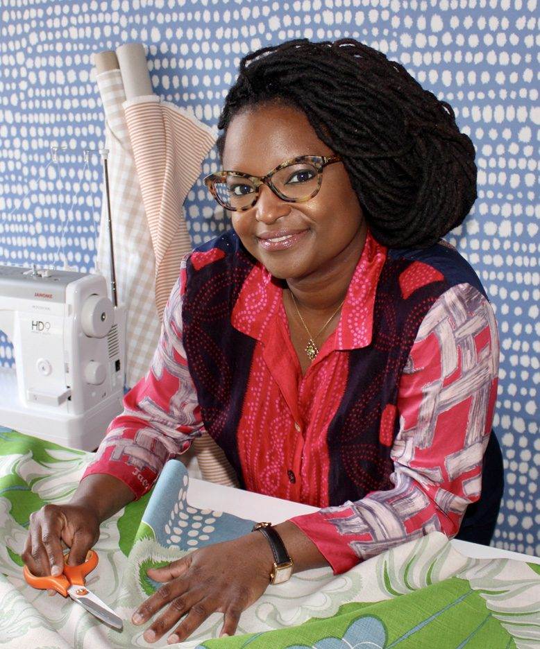 A woman with glasses is cutting fabric for made to measure curtains.