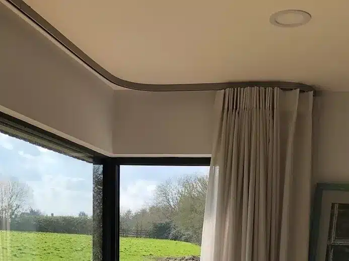 A room with a large bay window and curtains.